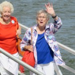 Two women standing and waving by railing on a yacht