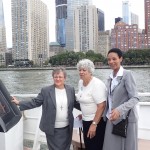 Three ladies on the deck of a yacht with NYC skyline behind them