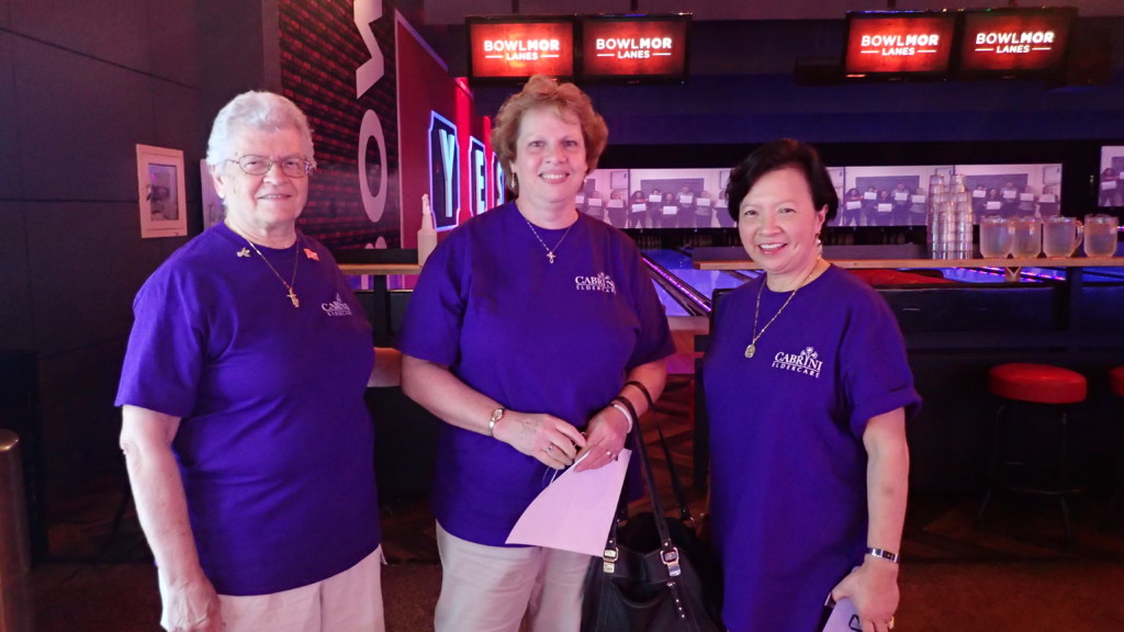 2018 Bowling FUNdraiser at bowling alley three women with blue Cabrini Foundation shirts in front of bowling lanes