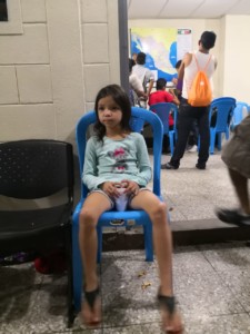 Honduran Migrant girl sitting in hallway with a glass of water