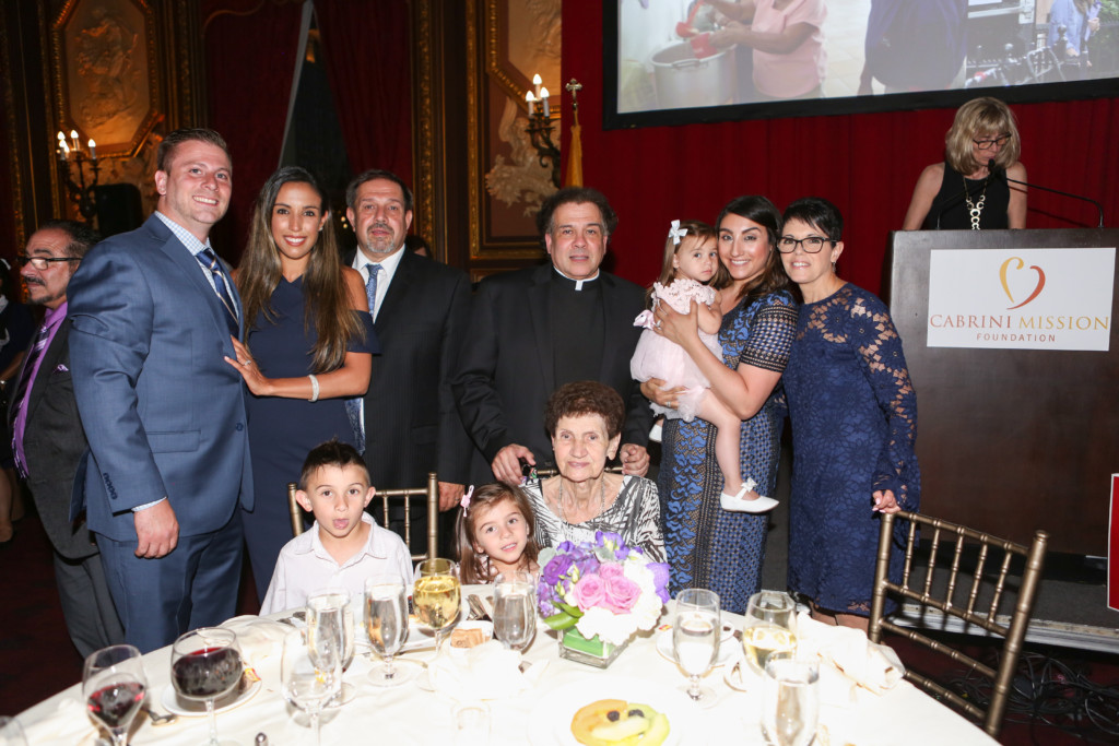 Cabrini Mission 20th Anniversary Gala attendees with children in front of table and podium