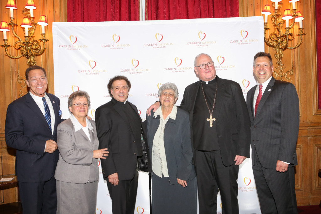 Cabrini Mission 20th Anniversary Gala attendees in front of Cabrini Mission Logo