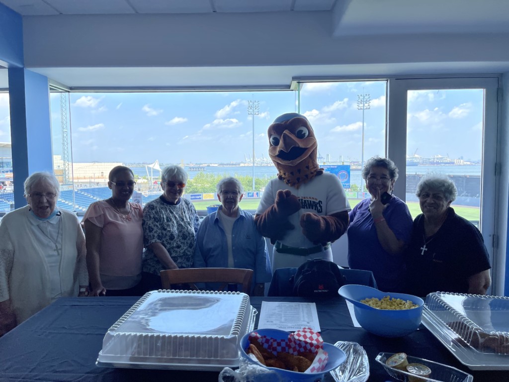 Cabrini Mission Foundation posing with Ferrhawks costumed mascot in skybox