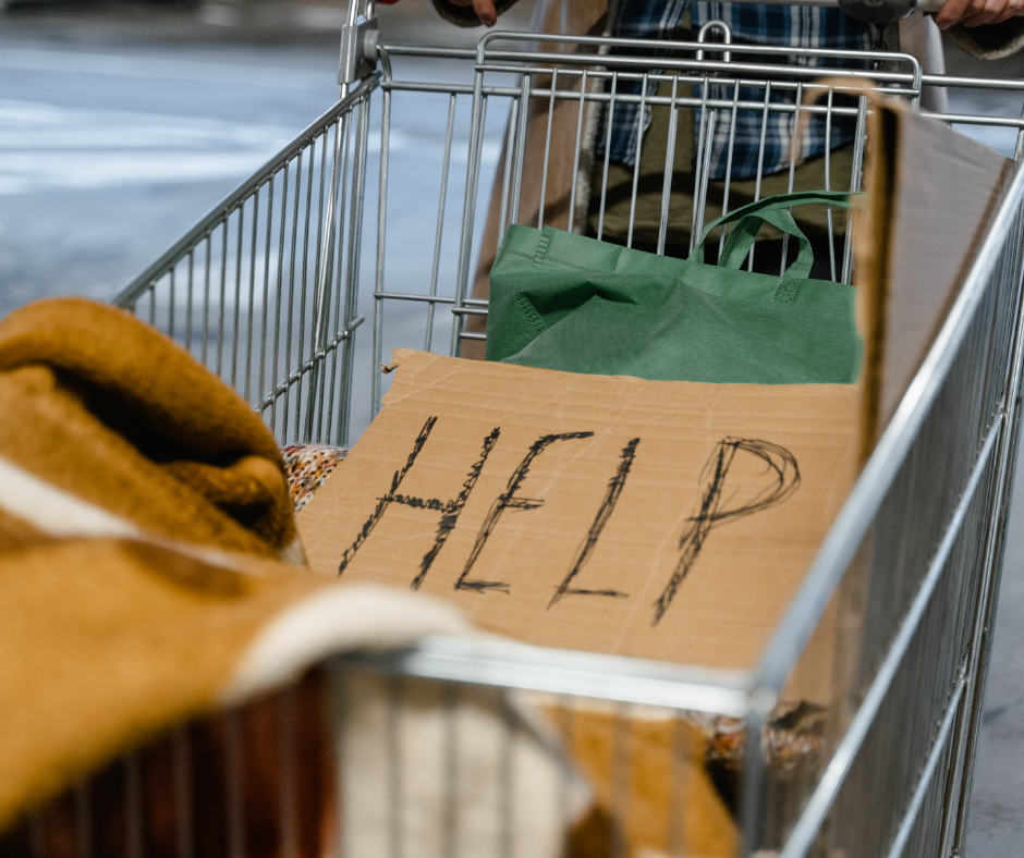 Shopping cart with cardboard sign reading "Help"